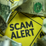 A yellow scam alert sign placed over the top of a money shaped tree is depicting financial fraud