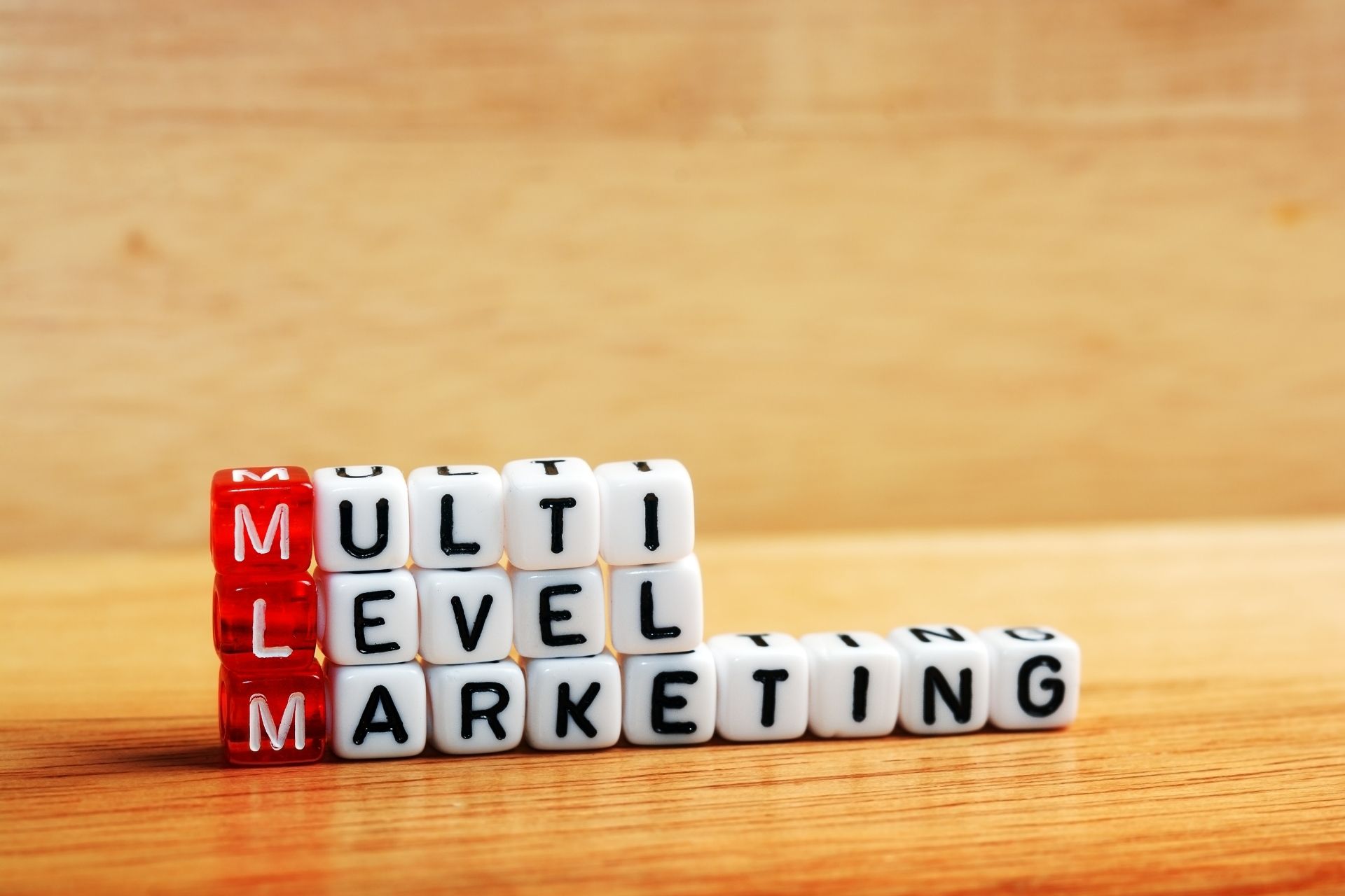3 rows of dice, red and white spelling mlm and multi level marketing and giving caution to upfront fees
